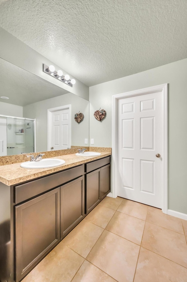 bathroom featuring vanity, a textured ceiling, tile patterned floors, and a shower with shower door