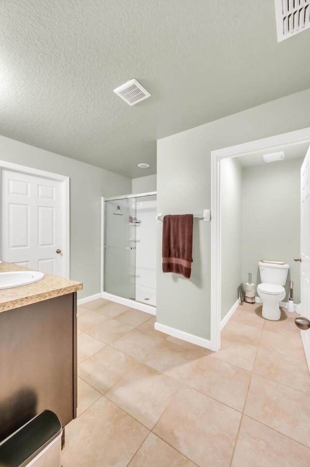 bathroom featuring tile patterned flooring, vanity, a textured ceiling, and walk in shower