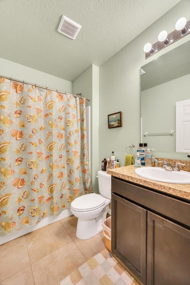 bathroom with tile patterned floors, vanity, a textured ceiling, and toilet