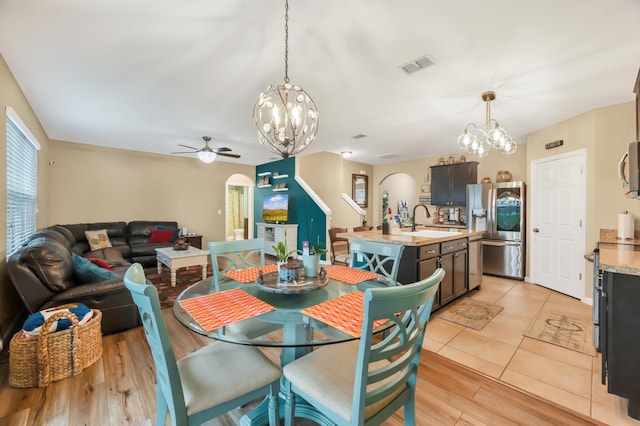 dining area with sink, light hardwood / wood-style floors, and ceiling fan with notable chandelier