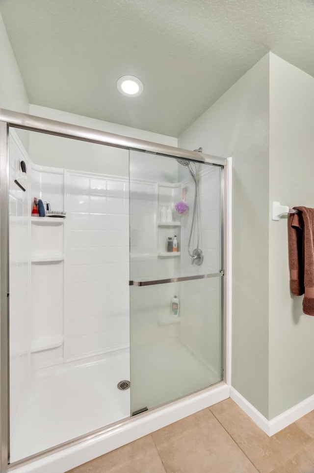 bathroom featuring tile patterned floors, a shower with door, and a textured ceiling