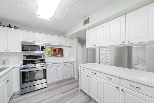 7579 NW 79th Ave Unit 201, Tamarac, FL 33321 - kitchen with visible vents, light countertops, a textured ceiling, light wood-style flooring, and appliances with stainless steel finishes