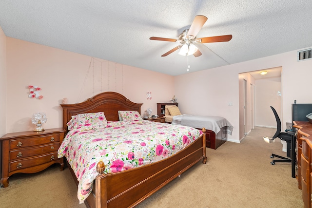 bedroom featuring ceiling fan, light carpet, and a textured ceiling