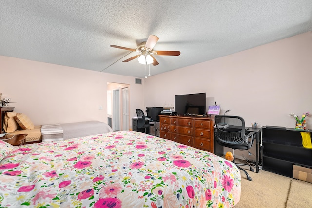 bedroom with ceiling fan, light colored carpet, and a textured ceiling