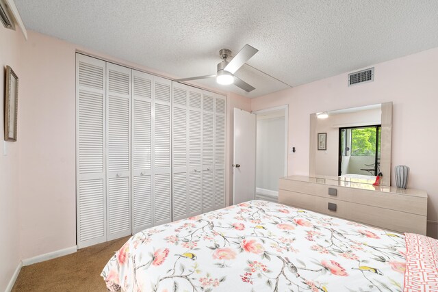 carpeted bedroom featuring ceiling fan, a closet, and a textured ceiling