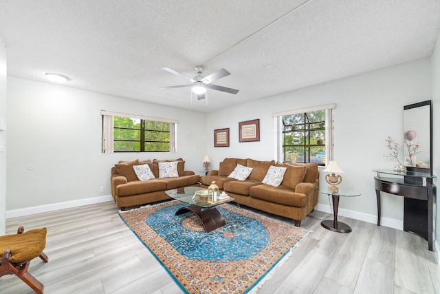 living room with a textured ceiling, light hardwood / wood-style flooring, a wealth of natural light, and ceiling fan