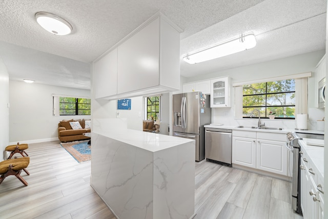 kitchen with sink, white cabinets, stainless steel appliances, and light hardwood / wood-style flooring