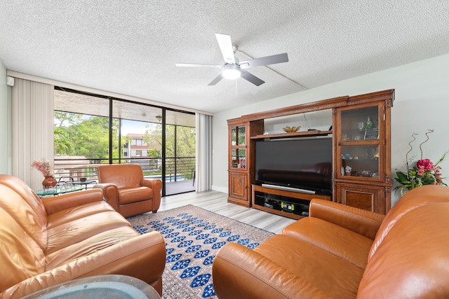 living room featuring a wall of windows, ceiling fan, a textured ceiling, and light wood-type flooring