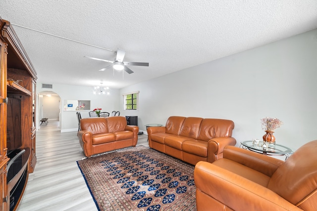 living room with ceiling fan, light hardwood / wood-style floors, and a textured ceiling