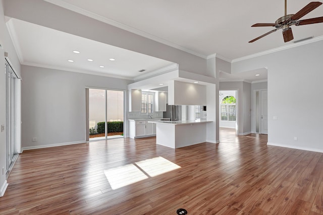 unfurnished living room with hardwood / wood-style flooring, sink, crown molding, and ceiling fan