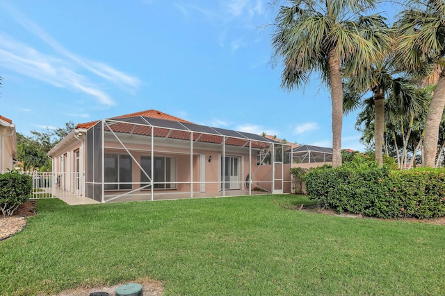 back of house featuring glass enclosure and a lawn