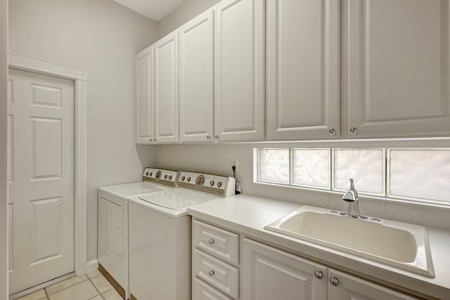 clothes washing area featuring light tile patterned flooring, cabinets, washer and dryer, and sink