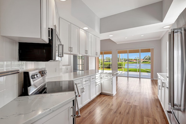 kitchen with kitchen peninsula, appliances with stainless steel finishes, decorative backsplash, light stone countertops, and white cabinets