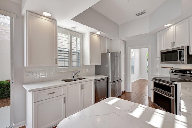 kitchen with appliances with stainless steel finishes, white cabinets, and sink