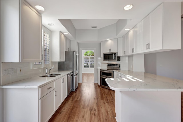 kitchen with white cabinets, kitchen peninsula, sink, and stainless steel appliances