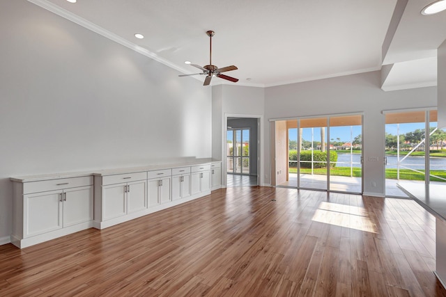 unfurnished living room with ceiling fan, light wood-type flooring, and crown molding