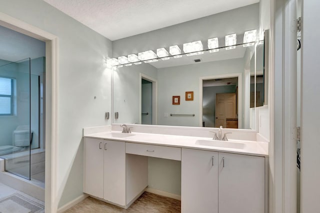 bathroom featuring a textured ceiling, vanity, and an enclosed shower