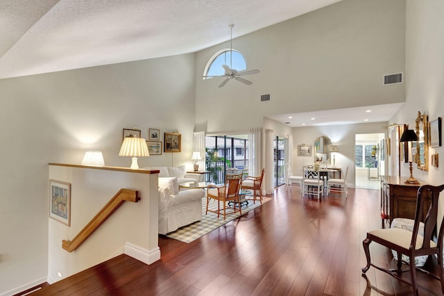 living room featuring ceiling fan, high vaulted ceiling, dark wood-type flooring, and a textured ceiling