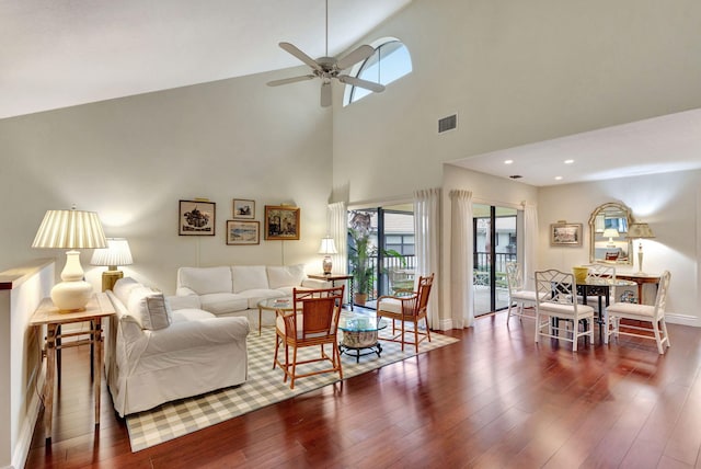 living room featuring ceiling fan, dark hardwood / wood-style flooring, and a towering ceiling