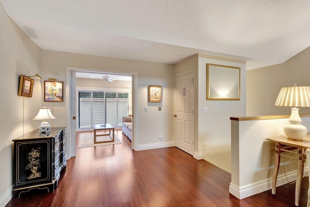 corridor with a textured ceiling and dark hardwood / wood-style floors