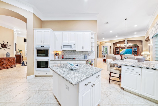 kitchen featuring white cabinets, light stone countertops, decorative light fixtures, a kitchen island, and stainless steel appliances