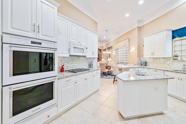 kitchen with white cabinets, appliances with stainless steel finishes, and ornamental molding