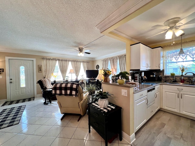 kitchen featuring kitchen peninsula, white cabinetry, sink, and crown molding