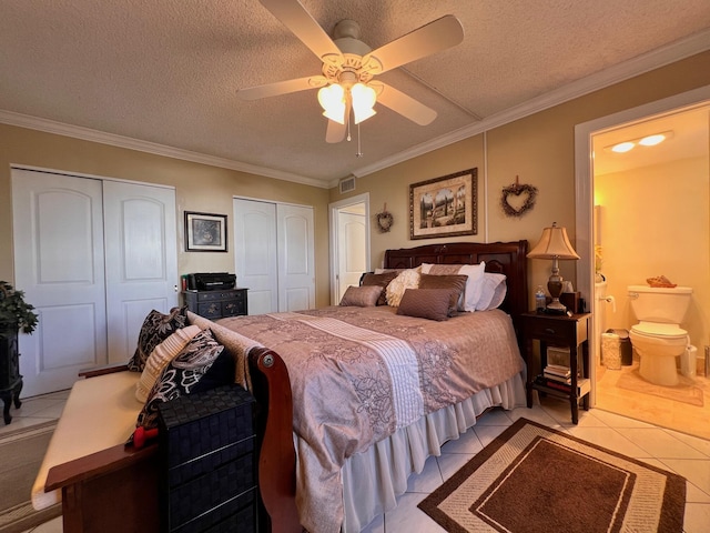 tiled bedroom featuring ensuite bath, ceiling fan, ornamental molding, a textured ceiling, and multiple closets