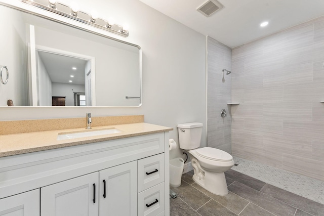 bathroom featuring tiled shower, vanity, and toilet