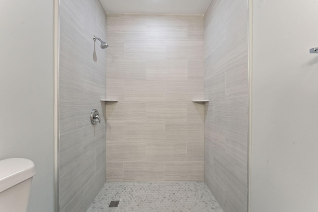 bathroom featuring tiled shower and toilet