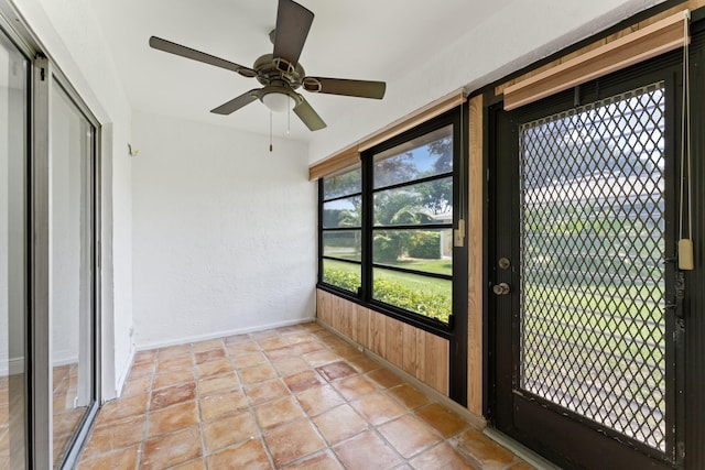 unfurnished sunroom with ceiling fan