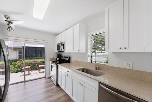 kitchen with light stone counters, stainless steel appliances, sink, light hardwood / wood-style flooring, and white cabinets