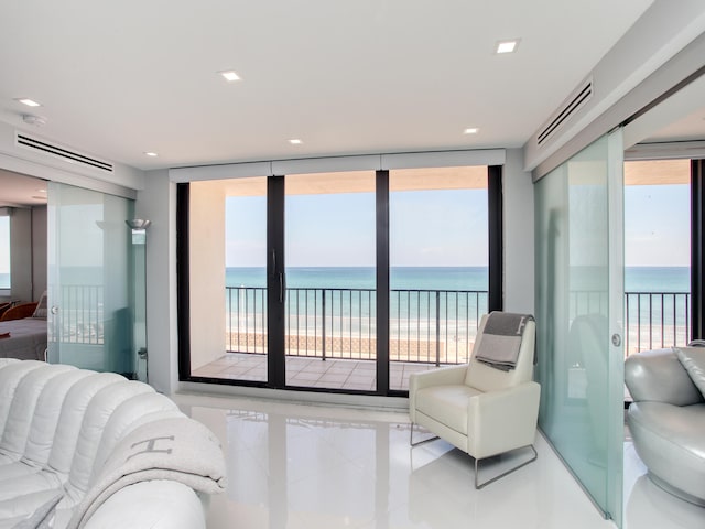 bedroom with a view of the beach, a water view, and multiple windows