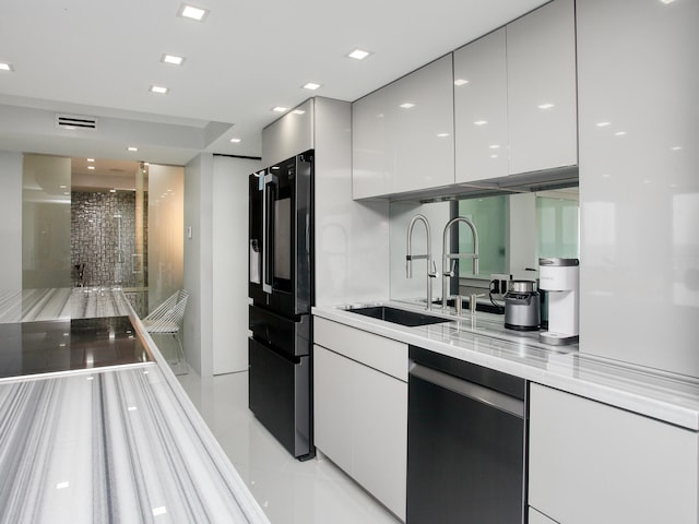 kitchen featuring dishwasher, sink, light tile patterned floors, black refrigerator, and white cabinets