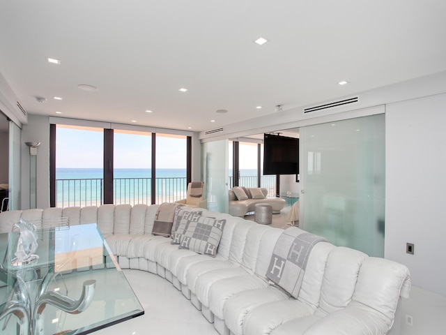 tiled living room with floor to ceiling windows, a water view, and plenty of natural light