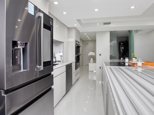 kitchen featuring black appliances, light tile patterned flooring, and white cabinetry