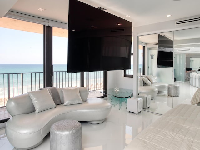 tiled living room featuring plenty of natural light, a water view, and a beach view