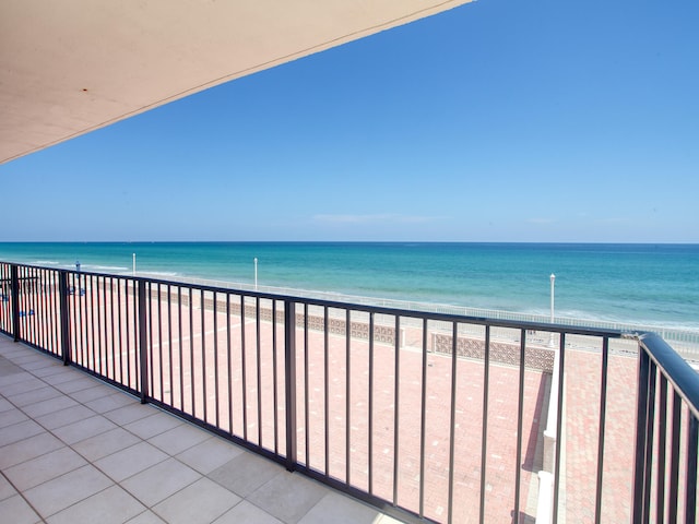 balcony with a water view and a view of the beach