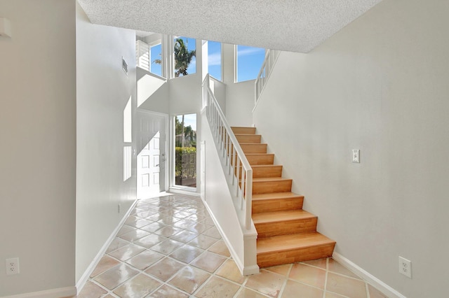 stairway featuring tile patterned floors, a textured ceiling, and a high ceiling