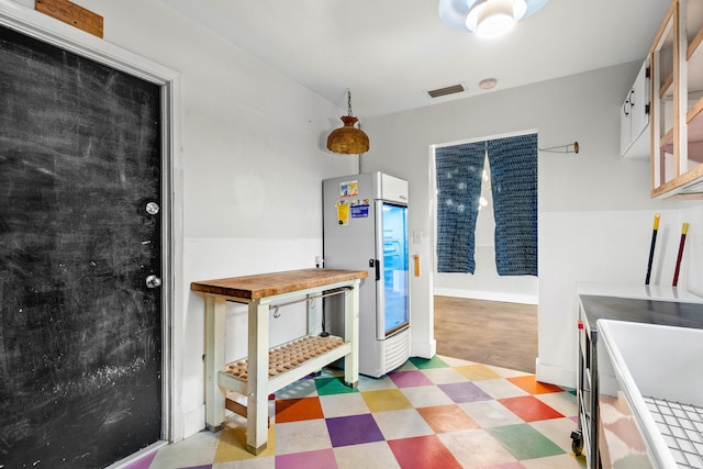 kitchen featuring white cabinets, wooden counters, and fridge