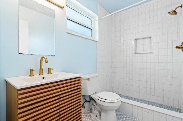 bathroom featuring toilet, vanity, tiled shower, and tile patterned floors