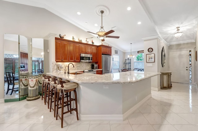 kitchen with stainless steel appliances, a kitchen breakfast bar, kitchen peninsula, lofted ceiling, and ornamental molding