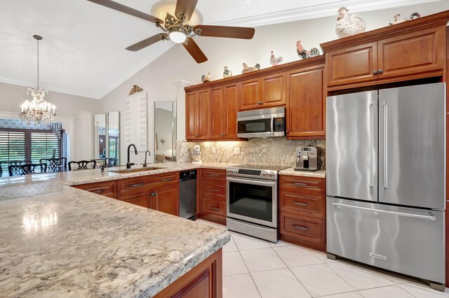 kitchen with appliances with stainless steel finishes, ornamental molding, ceiling fan with notable chandelier, vaulted ceiling, and sink