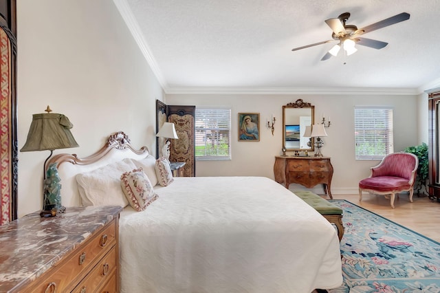 bedroom with ceiling fan, light hardwood / wood-style flooring, a textured ceiling, and ornamental molding