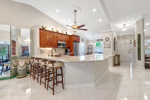 kitchen with lofted ceiling, a kitchen breakfast bar, crown molding, kitchen peninsula, and stainless steel appliances