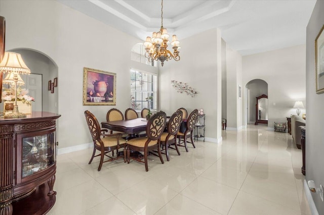 tiled dining room with a tray ceiling and a chandelier