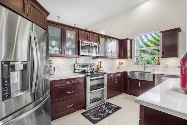 kitchen with light tile patterned floors, backsplash, stainless steel appliances, and sink