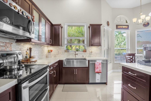 kitchen featuring stainless steel appliances, sink, light tile patterned floors, pendant lighting, and a chandelier