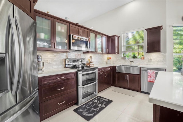 kitchen with appliances with stainless steel finishes, backsplash, light tile patterned floors, and sink