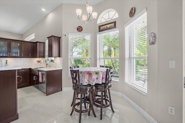 tiled dining space featuring sink, a wealth of natural light, and a chandelier